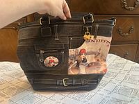 Front view of denim tote showing London graphic, belt trim, hardware