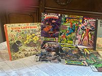 Group of Superman comics and Little Ladybird book displayed on table