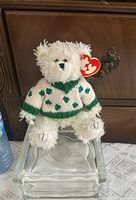 Full view of Flannigan bear seated, showing overall appearance and sweater