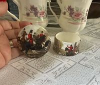 Open trinket box showing hunting scene on lid and body with mugs in background