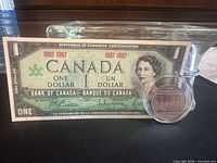 Front of Centennial banknote and obverse of commemorative coin