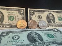 Fronts of two $2 notes and three Bicentennial half dollars