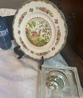Front view of Chelsea Bird plate on easel, glass surface and shell visible