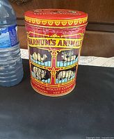 Front view of 1979 Nabisco Barnum's Animals tin beside water bottle for scale