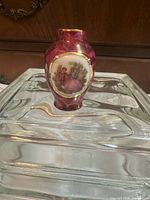 Front view of burgundy Limoges miniature vase on glass stand