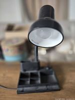 Overall view of black desk lamp showing gooseneck, bulb, and organizer base