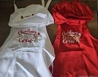 Top-down view of both aprons and hats laid flat showing colors, embroidery and pockets