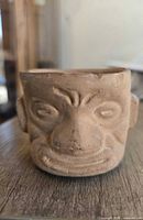 Front view showing sculpted face details of terracotta pot
