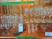 Cabinet shelves showing multiple sizes of clear stemware and boxed Dalex measure
