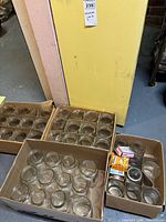 Four cardboard boxes containing rows of clear mason jars; boxed snap lids visible