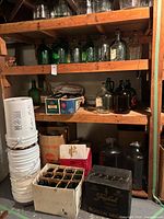 Shelves with multiple glass carboys, jugs, bottle boxes and stacked buckets