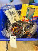 Blue tote containing loose audio cables, earbuds in bags, Sony Walkman boxed, various adapters