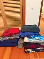Two stacks of assorted fleece blankets on wood floor