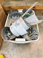Top view of plastic tote holding multiple metal cans filled with assorted nails, screws, hose clamps and a sleeve of finish nails