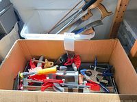 Overview of box with various clamps and background hand saws