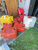 Overall view of assorted fuel containers grouped outside shed