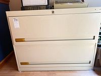 Front view of beige 2-drawer lateral file cabinet showing recessed pulls and lock