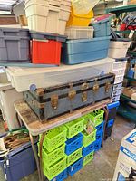 Stacked plastic bins with steamer trunk beneath