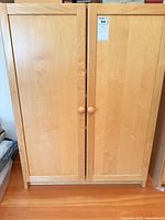 Front view of maple veneer storage cabinet with two doors and round knobs
