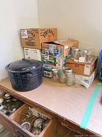 Overall view showing enamel pot, several liquor boxes of jars, loose jars, drawer of more jars