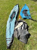 Fabric kayak skin sections, frame poles in bag, paddles on grass