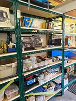 Full view of shelving unit showing five particleboard shelves within green steel frame