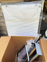 Sealed flip-chart paper pad leaning behind box with easel parts