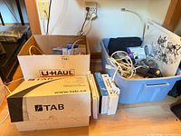 Two boxes and tote containing cables, router, software boxes