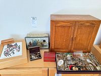Overall shot of storage boxes, cabinet, cases and open jewelry case filled with assorted costume pieces