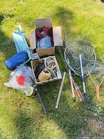 Group shot of rods, reels, nets, rope, buoys, binder, tray and accessory crate on grass