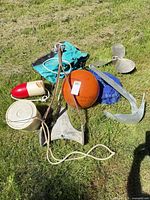 All items laid out on grass: anchors, propeller, buoys, rope, bags