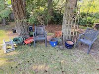 Wide shot showing both chairs, wagon, hose, multiple planters