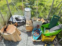 Overview of all items inside greenhouse, showing stump, tarp, perlite bag, boxes, crate with tools