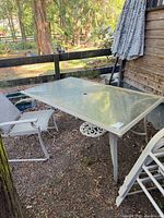rectangular glass-top table, chair and umbrella visible