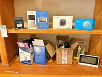 Entire lot on shelving showing boxed Ring, Blink, Echo Dot, Smart Plug, Panasonic phone, desk clock