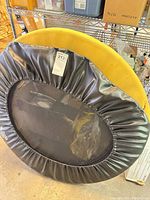 Black mini trampoline with yellow pad behind, full view