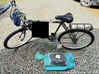 Full left-side view of TerraRunner bike with rear rack, kickstand, front bag and accessories on ground