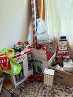 Grouped holiday decor items including stocking, candles, votive holders, snowman sign and boxes