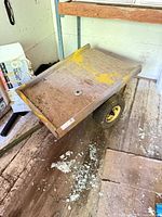 Top view of plywood deck garden cart showing yellow paint remnants and one pneumatic wheel
