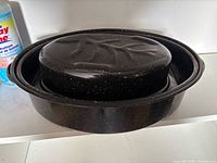 Nested black speckled enamel oval roasters showing base and lid profiles