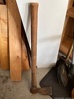 Full view of mattock showing wooden handle and rusted steel head