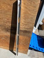 Full view of aluminum spirit level leaning against plywood background