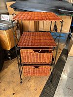 Front view of metal frame shelf with wicker top and two drawers