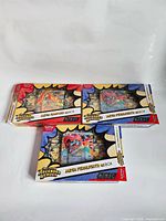 Three open Ascended Heroes EX boxes showing packaging and partially visible jumbo cards
