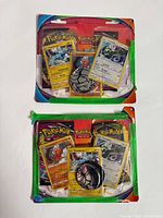 Two opened Pokémon blister packs with visible cards and coins