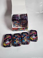 Display box opened showing multiple Pokémon mini tins stacked inside and five tins laid out front