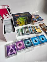 Overview of storage box filled with cards, collector box, stacked cards, sealed energy packs and boosters