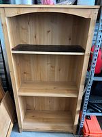 front view of light pine wood bookcase with three shelves