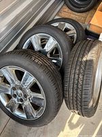 Stack of four tires, three showing chrome alloy rims