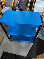 full view of blue three-shelf metal trolley showing handle and shelves